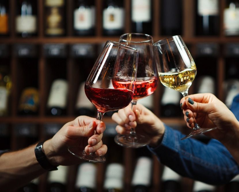 tres manos brindando con copas de vino de diferentes colores